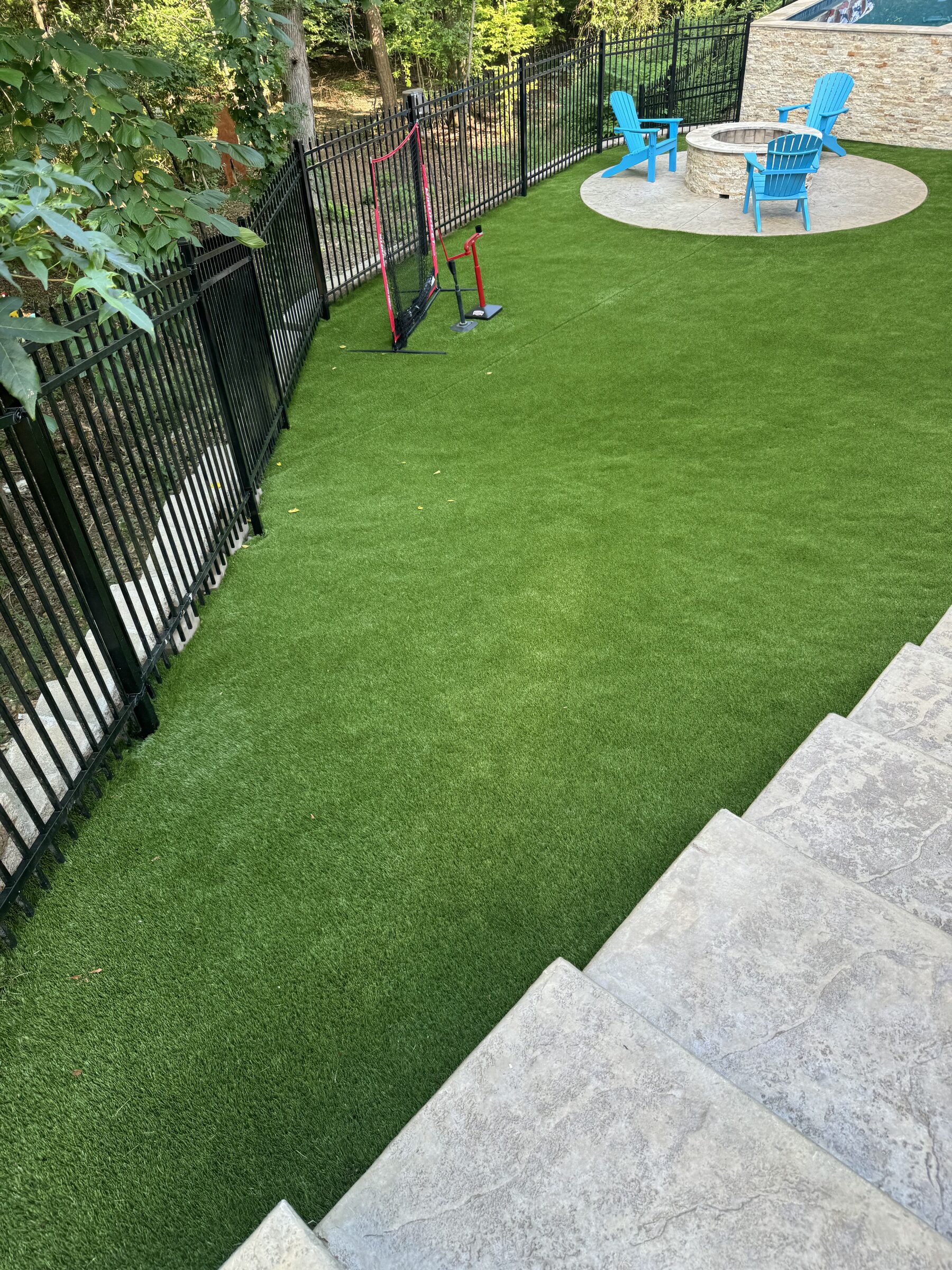 AstroTurf yard with fire pit and pool beyond