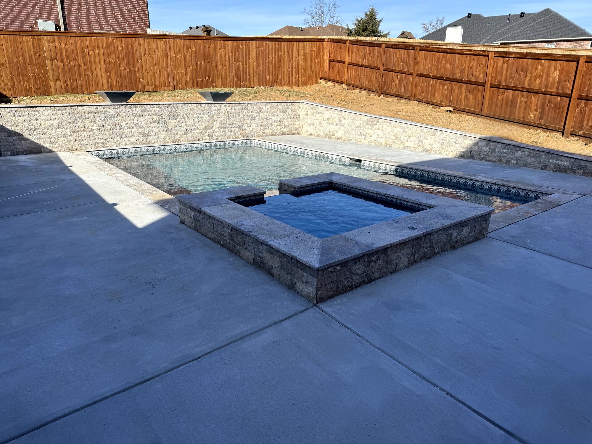 Pool, raised spa, and split-face travertine wall with water bowls